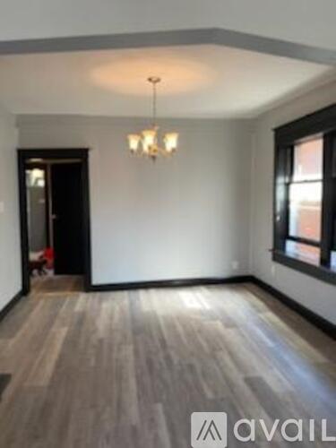 A room with wooden flooring and a chandelier hanging from the ceiling.