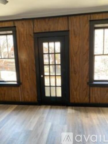 A room with a black door and wooden walls.