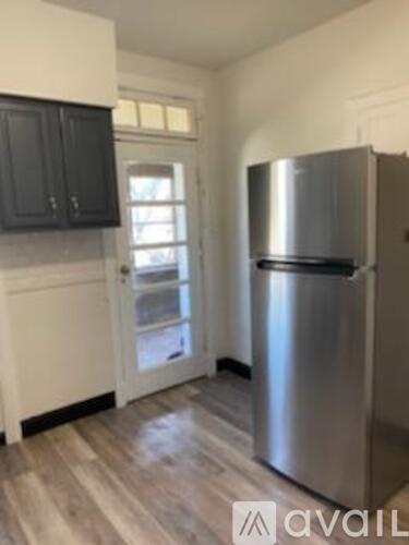 A kitchen with a stainless steel refrigerator and wooden flooring.