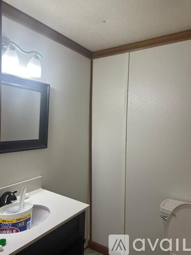 A bathroom with a toilet, sink, mirror and a white cabinet.