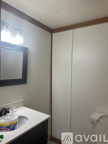 A bathroom with a toilet, sink, mirror and a white cabinet.