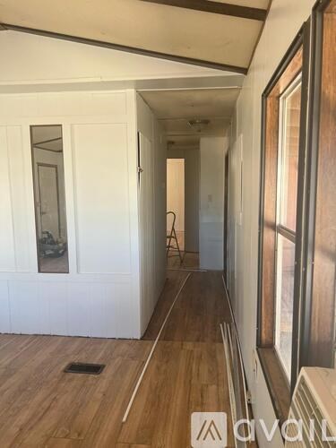 A hallway with wooden floors and white walls.
