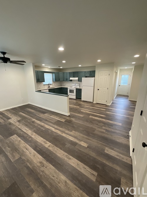 A kitchen with a wooden floor and a ceiling fan.