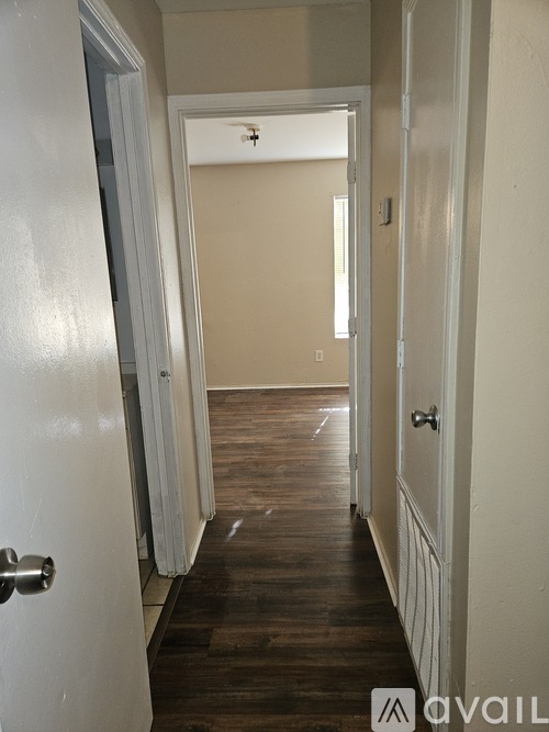 A hallway with a white door on the left and a white door on the right.