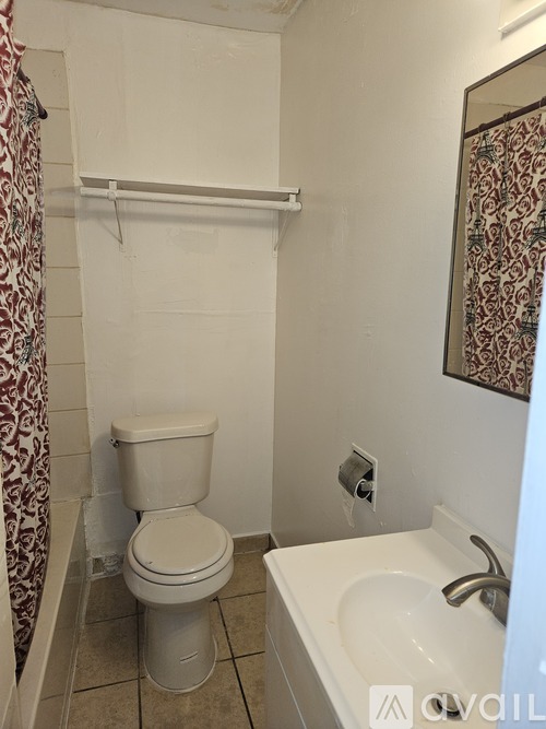 A white toilet sits next to a white sink in a small bathroom.