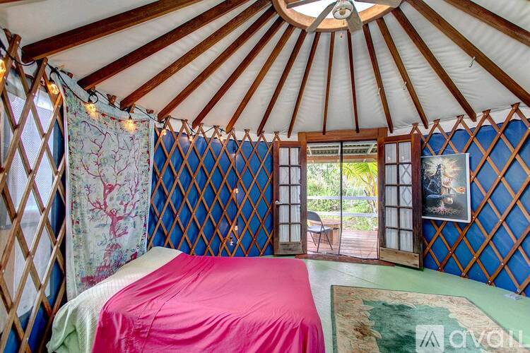 A bedroom with a pink bedspread and a canopy.