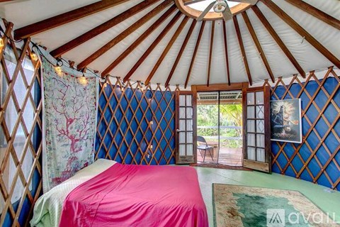 A bedroom with a pink bedspread and a canopy.