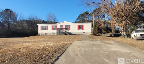 A white house with red shutters is for sale.