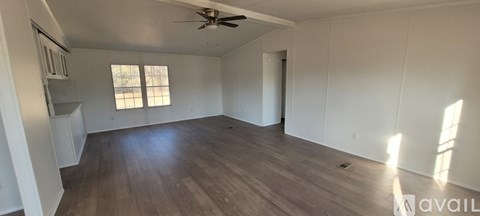 A spacious room with a ceiling fan and wooden flooring.