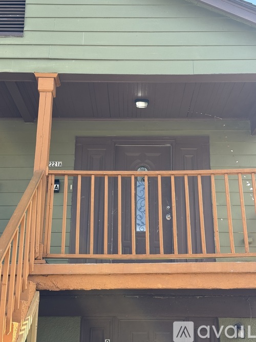 A balcony with a wooden railing and a door with a window above it.