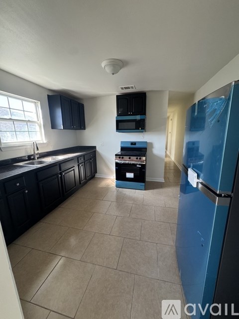 A kitchen with black cabinets and a blue fridge.