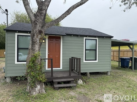 A small green house with a brown door and a brown porch.