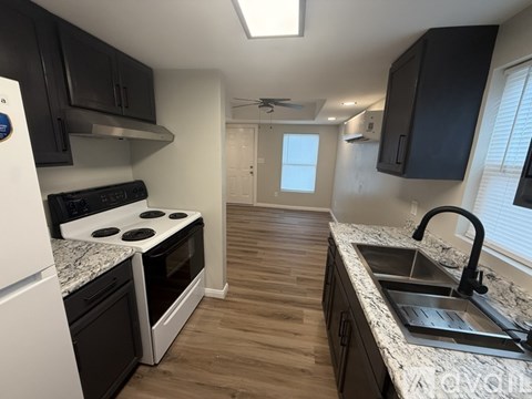 A kitchen with a white stove top oven and black cabinets.