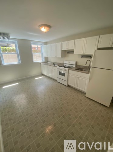 A kitchen with white appliances and a tiled floor.