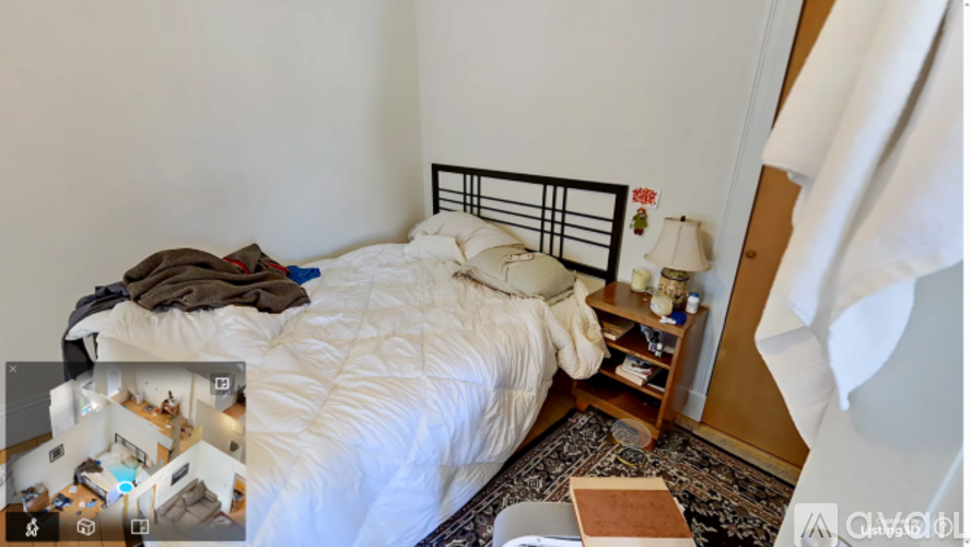 A bedroom with a white bed and a small wooden nightstand.