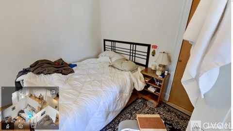 A bedroom with a white bed and a small wooden nightstand.