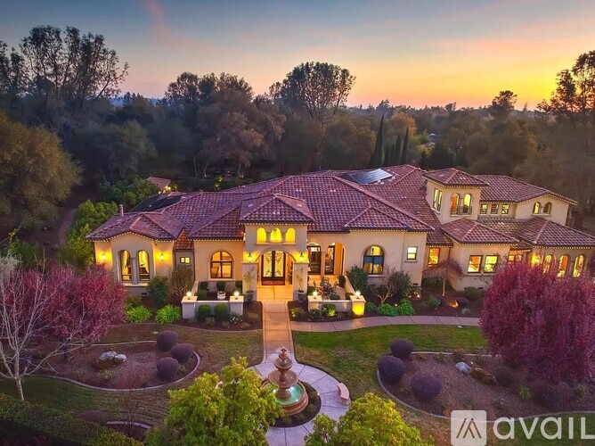 A large house with a red tiled roof and a garden in front.