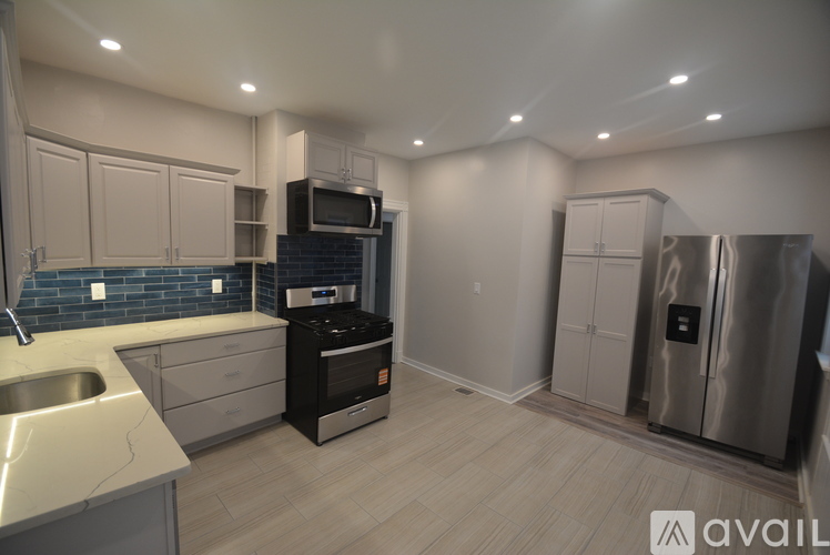 A modern kitchen with stainless steel appliances and wooden flooring.