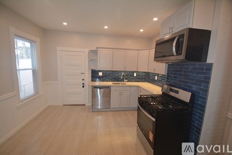 A kitchen with a black stove top oven and a white door.