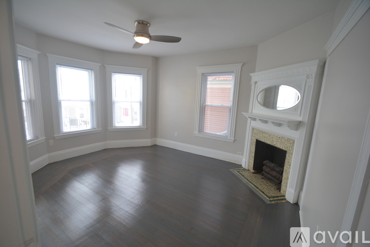 A living room with a fireplace and a ceiling fan.
