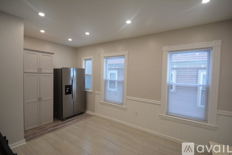 A kitchen with a fridge, cabinets and a window.