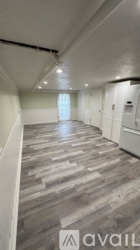 A long hallway with wood flooring and white walls.