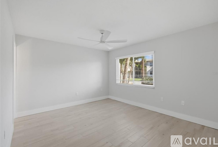 A spacious room with a window and a ceiling fan.