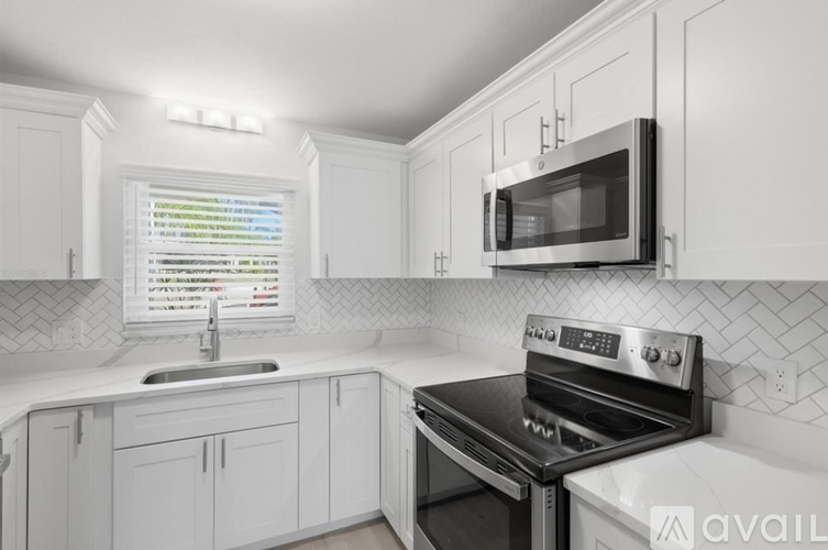 A modern kitchen with white cabinets and a black stove top oven.