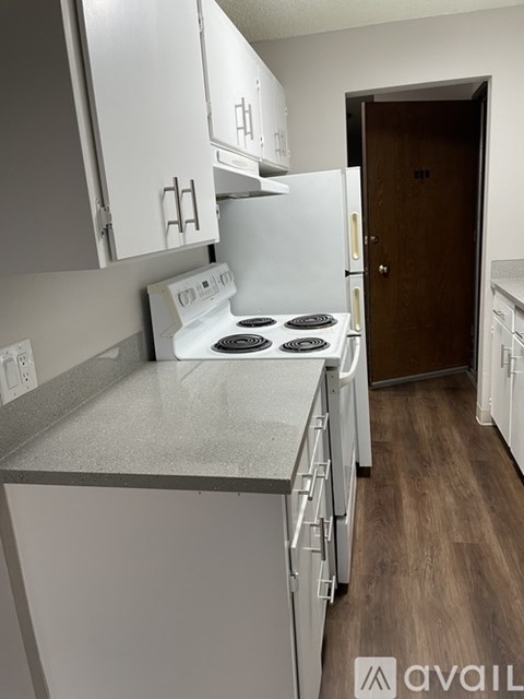 A kitchen with a white stove and cabinets.