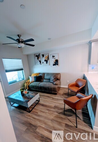 A living room with a grey couch, a coffee table, and two chairs.