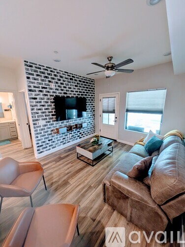 A living room with a brown leather couch and a brick wall.