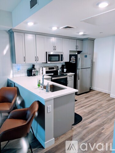 A kitchen with a blue counter and brown chairs.