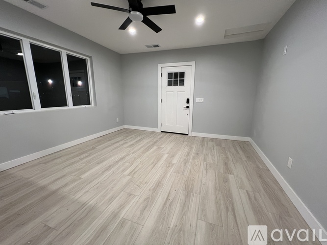 A room with a white door and a ceiling fan.