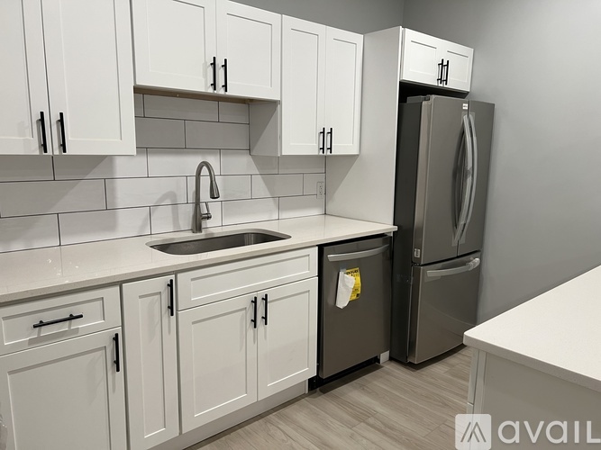A kitchen with white cabinets and a black fridge.