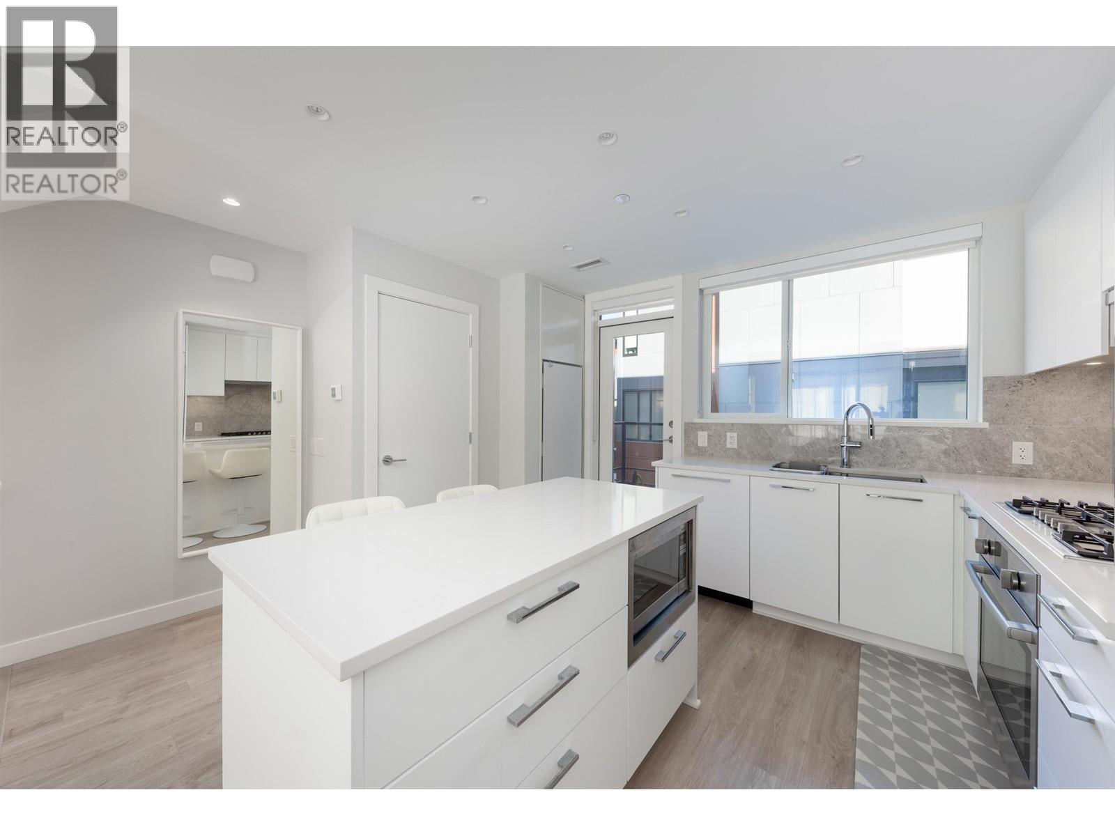 A white kitchen with a large island and stainless steel appliances.
