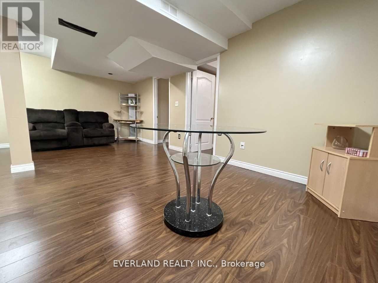 A room with a glass table and a black sofa.