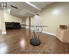 A room with a glass table and a black sofa.