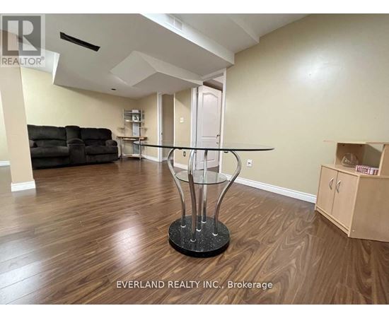 A room with a glass table and a black sofa.