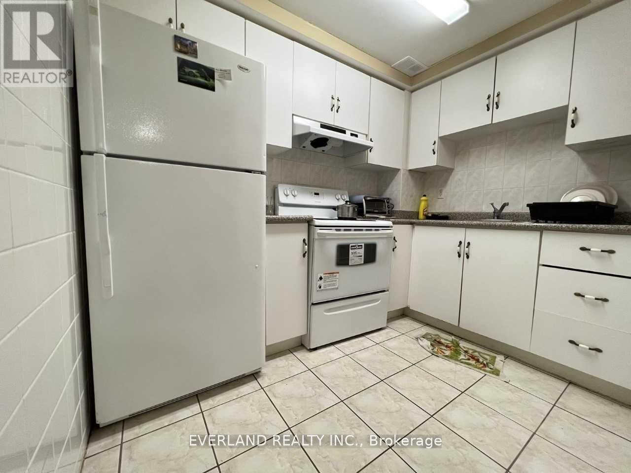 A kitchen with white cabinets and a white fridge.