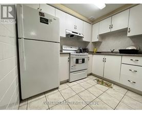 A kitchen with white cabinets and a white fridge.