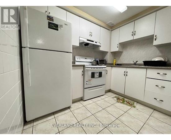 A kitchen with white cabinets and a white fridge.