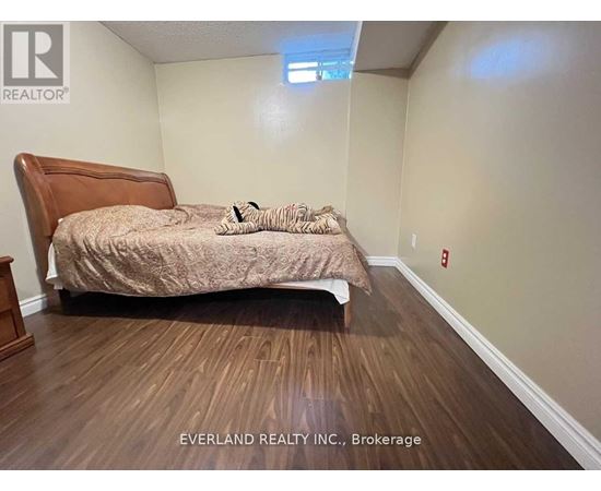 A bedroom with a bed, pillows, and a wooden headboard.