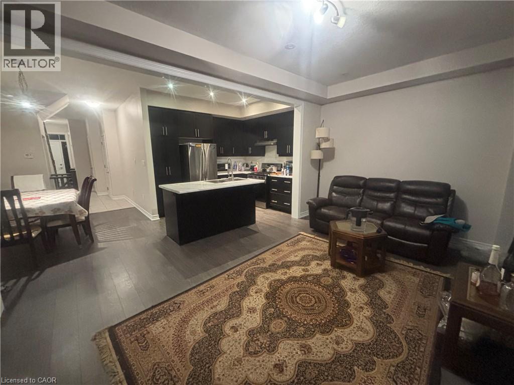 A living room with a rug, a couch, and a kitchen area in the background.