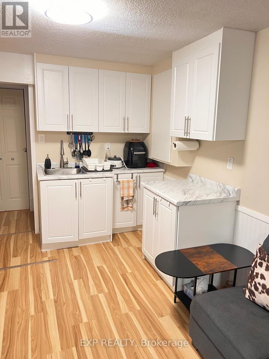 A kitchen with white cabinets and a wooden floor.