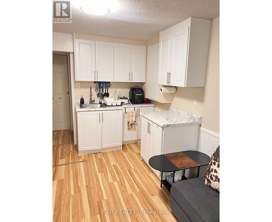 A kitchen with white cabinets and a wooden floor.
