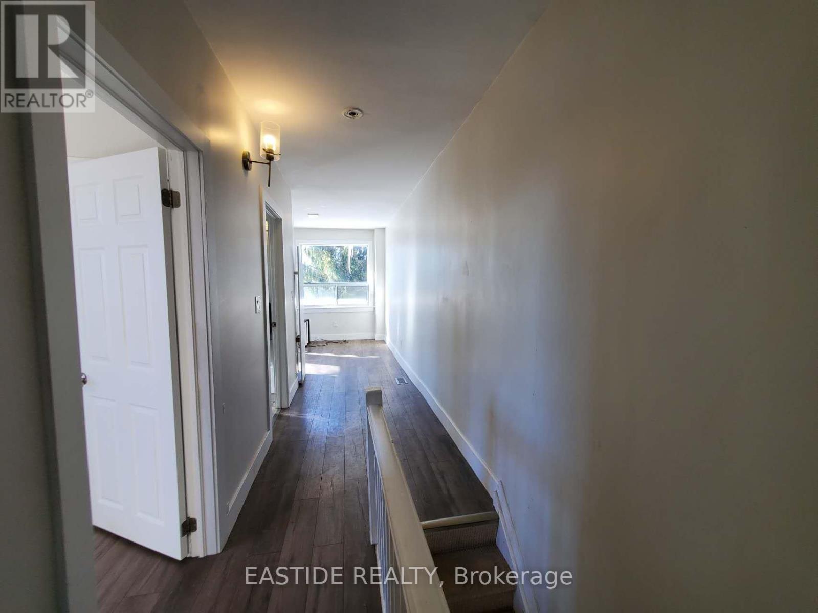 A hallway with a white door and a window in the distance.