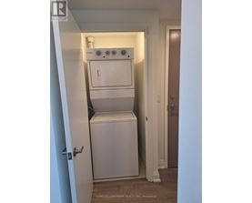 A white dryer and washer are stacked on top of each other in a small closet.