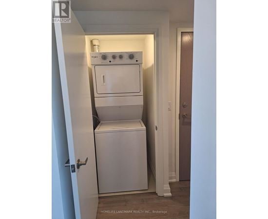 A white dryer and washer are stacked on top of each other in a small closet.
