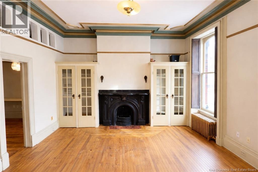 A large, empty room with a fireplace and wood floors.
