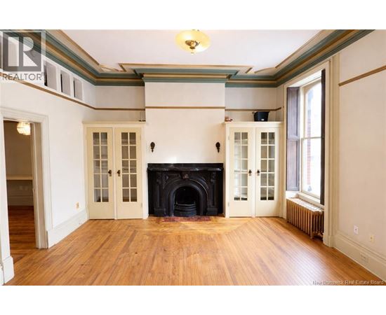 A large, empty room with a fireplace and wood floors.